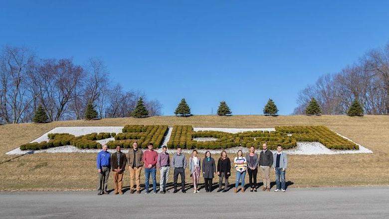 Group stands in front of bushes that spell out FedEx
