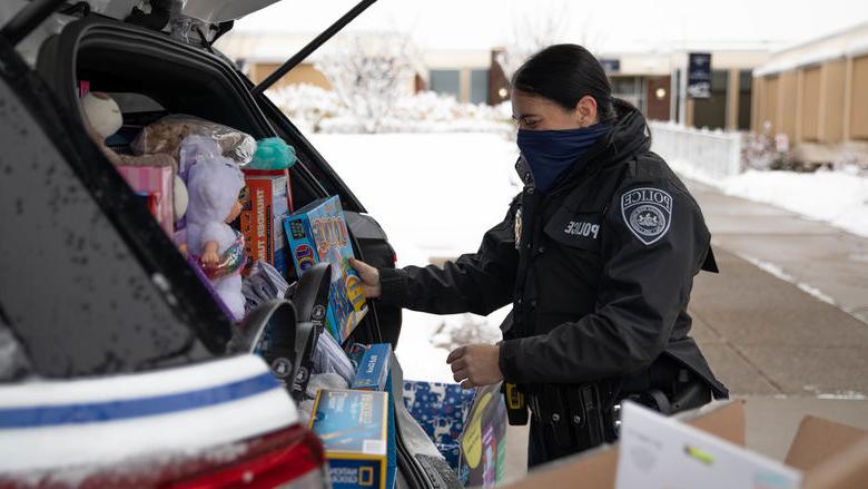 Police officer loading police cruiser with donated items